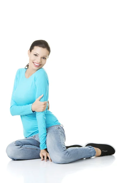 Jonge vrouw in casual kleding zittend op de vloer — Stockfoto