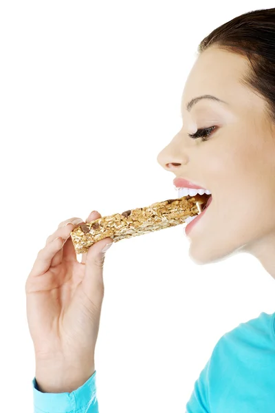 Jovem mulher comendo barra de doces de cereais — Fotografia de Stock