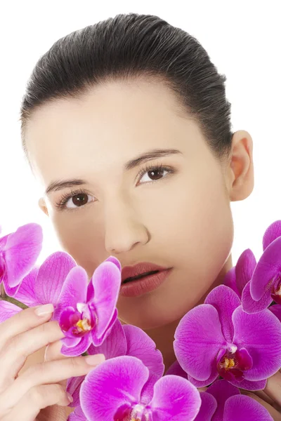 Mujer joven con piel sana y con flor de orquídea — Foto de Stock