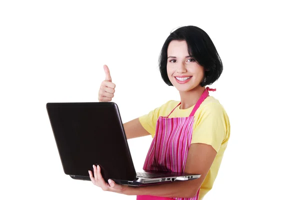 Mladá žena v růžové zástěře pomocí přenosného počítače — Stock fotografie