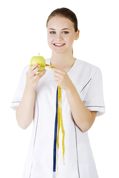 Lachende vrouw arts met een groene appel en meetlint. — Stockfoto