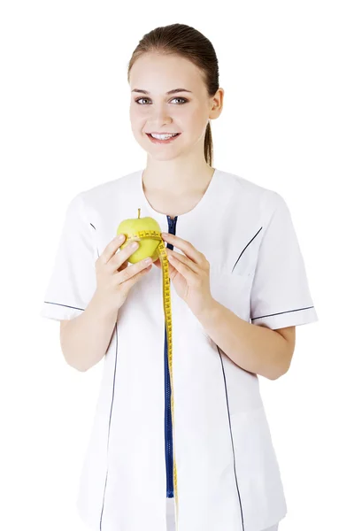 Femme médecin souriante avec une pomme verte et ruban à mesurer . — Photo