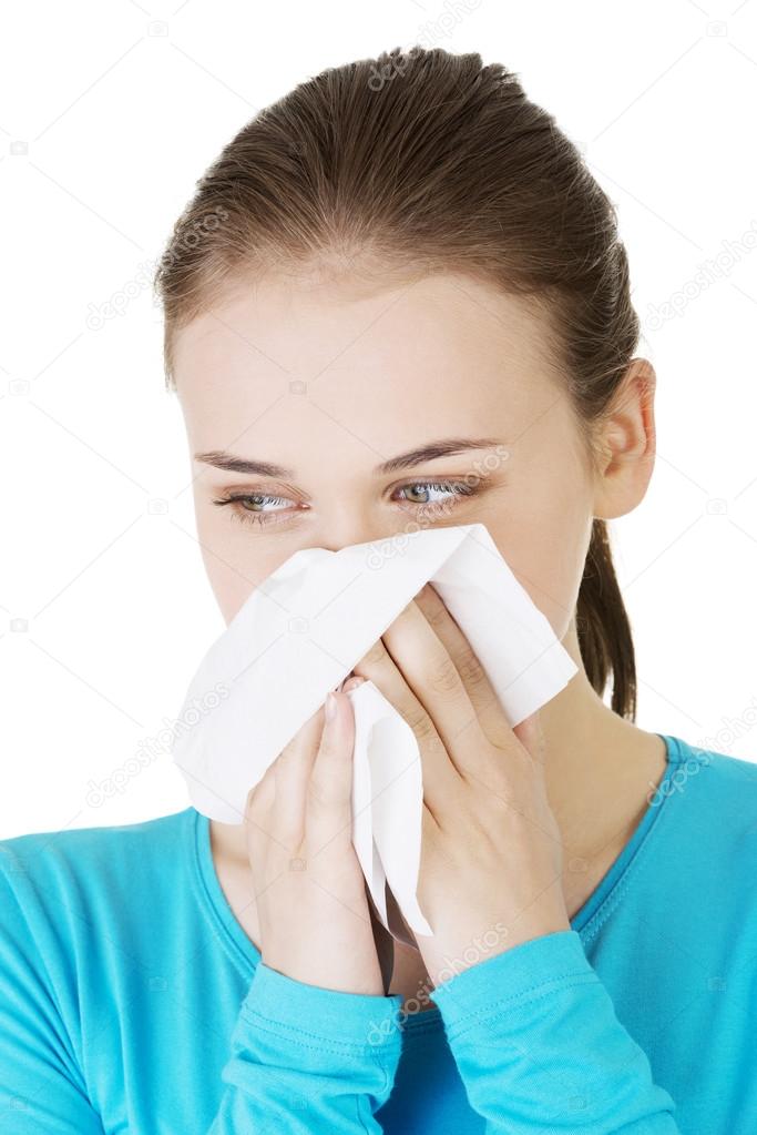 Young woman with tissue - sneezing. Allergy or cold.