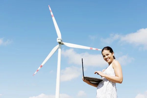 Chica adolescente con portátil junto a la turbina eólica . — Foto de Stock