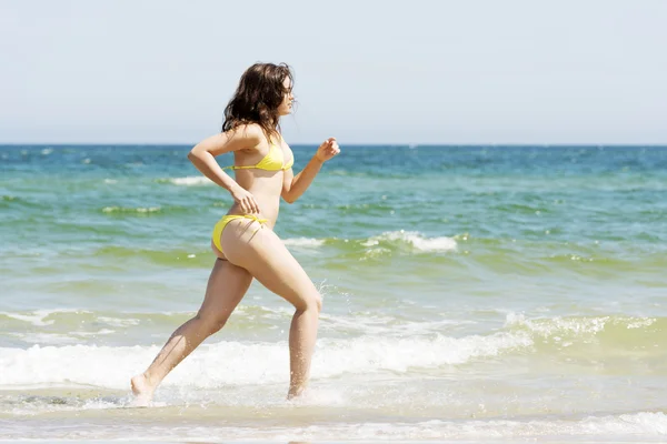 Glad kvinna kör på stranden — Stockfoto