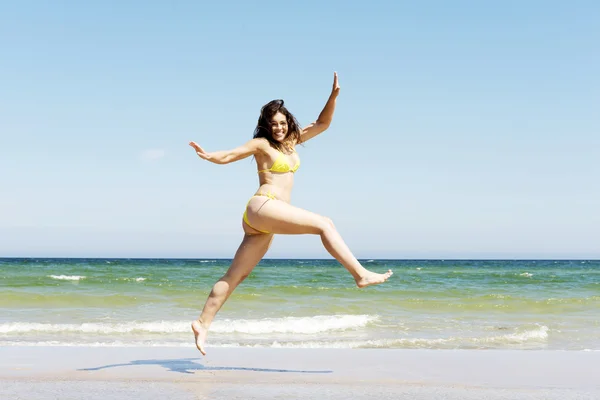 Lykkelig jente som hopper på stranda – stockfoto