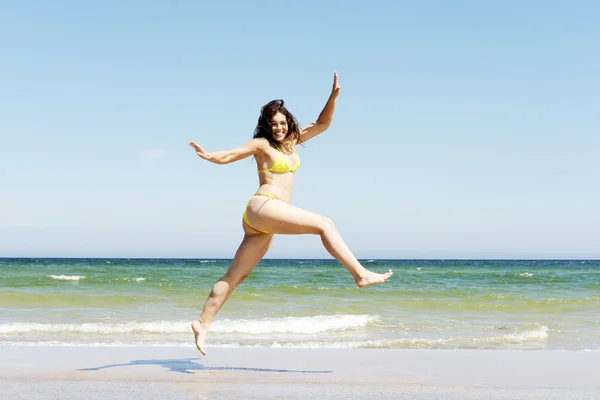 Gelukkig meisje springen op het strand — Stockfoto