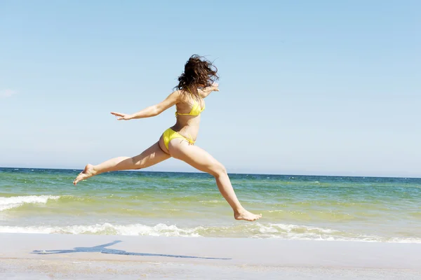 Счастливая девушка прыгает на пляже — стоковое фото