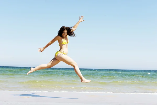 Lykkelig jente som hopper på stranda – stockfoto