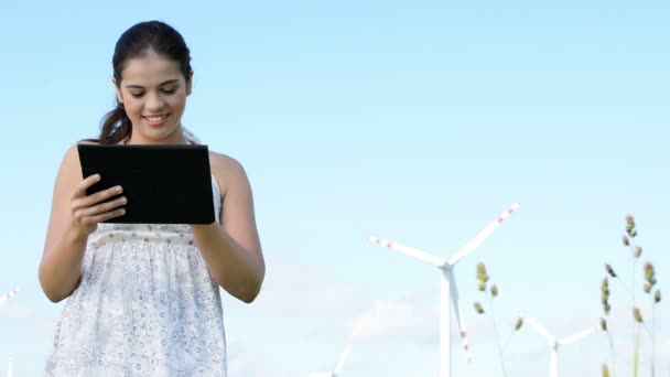 Teen girl with tablet computer next to wind turbine. — Stock Video