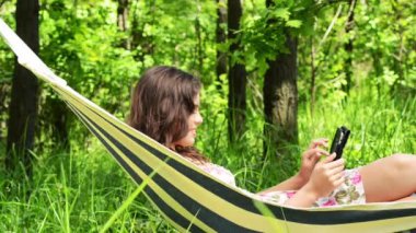 çekici bir kadın ile bir tablet bilgisayar bir hamakta yatan.