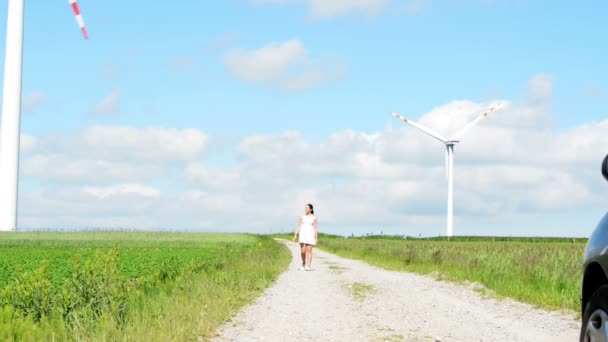 Glückliches Teenie-Mädchen neben Windkraftanlage. — Stockvideo