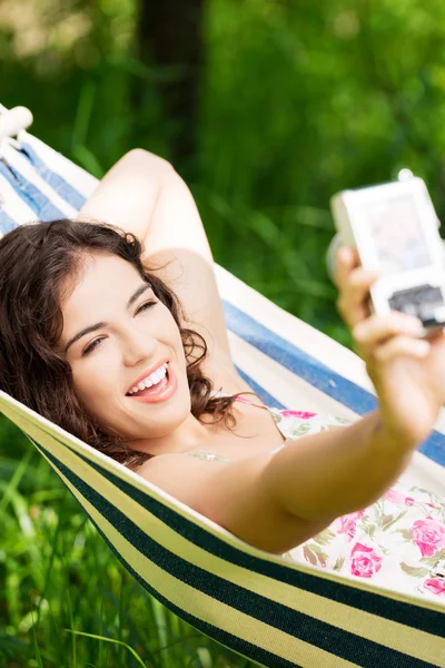 Mujer joven en una hamaca en el jardín haciendo instantánea . —  Fotos de Stock