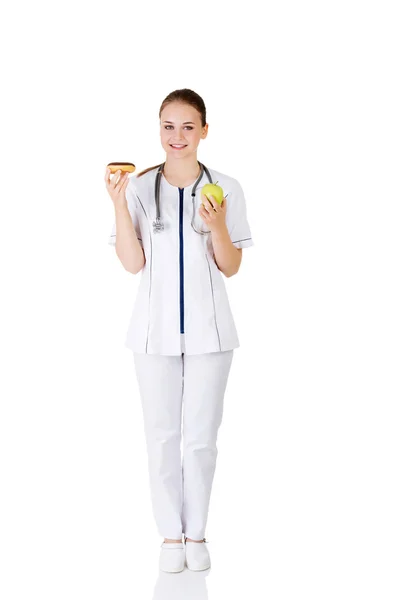 Diëtist holding zoete donut en verse gezonde groene appel. — Stockfoto