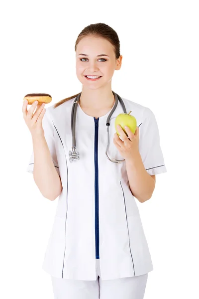 甘いドーナツ、新鮮な健康な緑のリンゴを保持している栄養士. — ストック写真