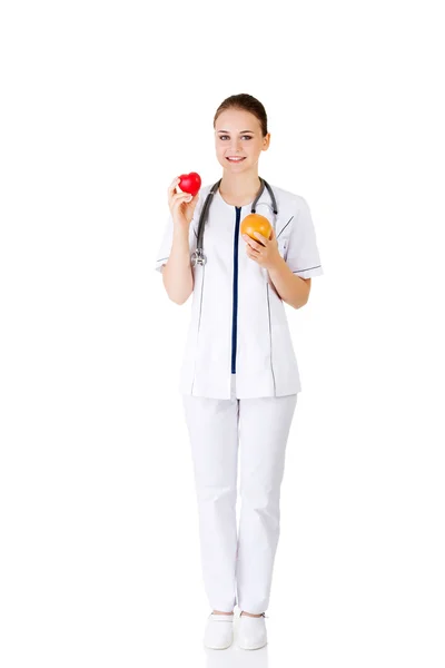 Médica feminina segurando toranja saudável e coração vermelho . — Fotografia de Stock