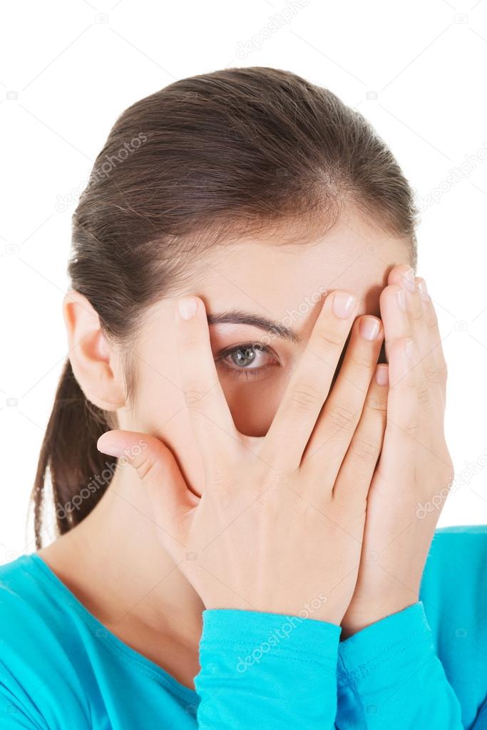 Shy teenage girl peeking through covered face