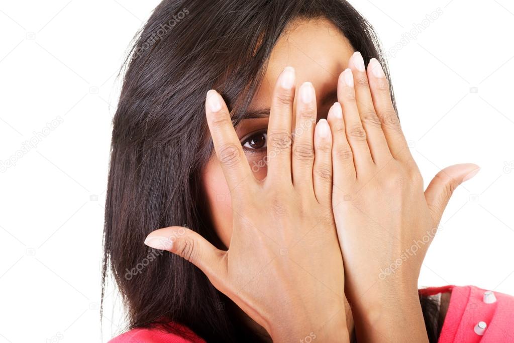 Shy woman peeking through covered face.