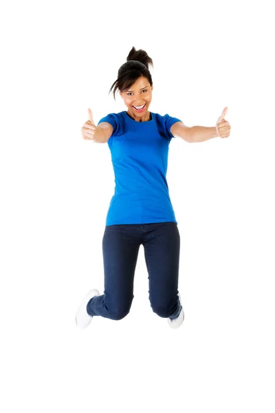 Junge glückliche Frau springt mit erhobenem Daumen in die Luft — Stockfoto