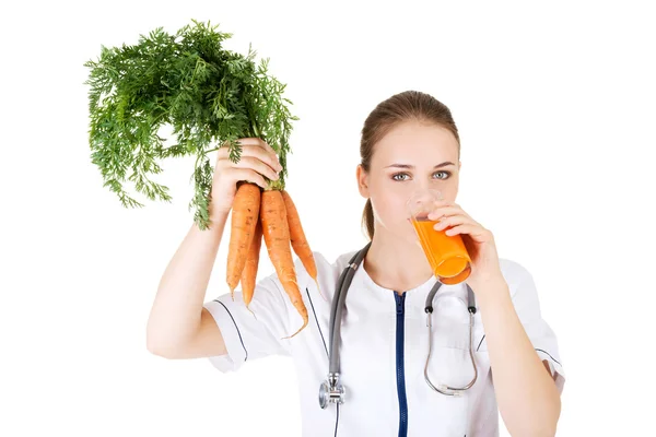 Vrouwelijke arts bedrijf gezond wortelen. — Stockfoto