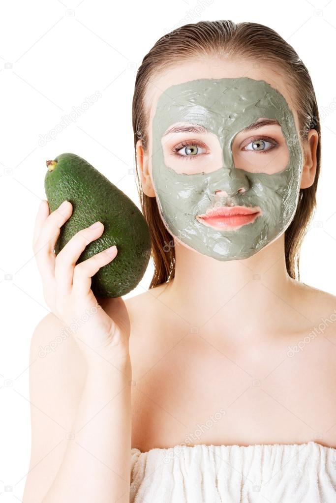 Beautiful woman with green avocado clay facial mask