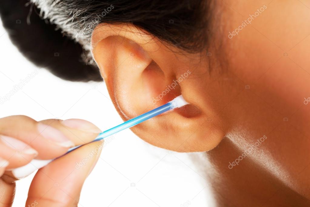 A young, beautiful, happy woman cleans her ear