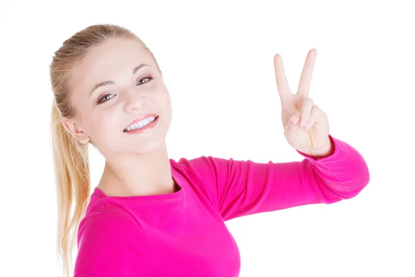 Glückliches junges Teenager-Mädchen zeigt Siegeszeichen — Stockfoto