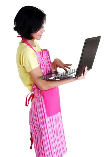 Jonge vrouw in roze appron met behulp van laptop — Stockfoto