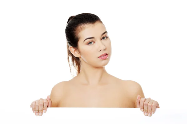 Sexy naked brunette holding empty board — Stock Photo, Image