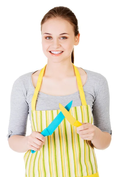 Aantrekkelijke vrouw in keuken schort met messen. — Stockfoto