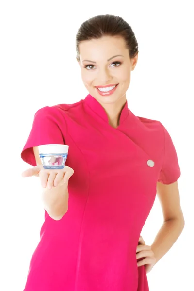 Beautiful attractive beautician holding a cream. — Stock Photo, Image