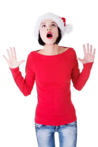 Attraente giovane donna che guarda in alto, indossa il cappello da Babbo Natale. mani aperte — Foto Stock