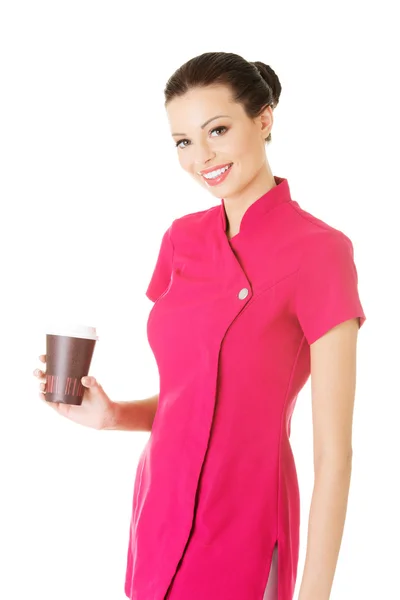Mulher atraente em uniforme rosa segurando um copo . — Fotografia de Stock