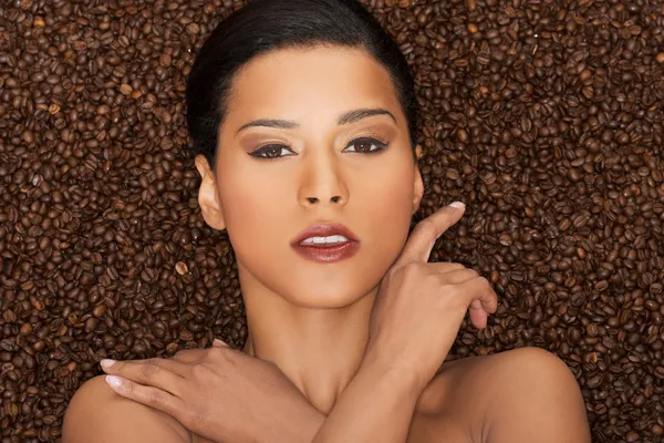 Attractive woman lying in coffee grains. Fron view. Closeup. — Stock Photo, Image