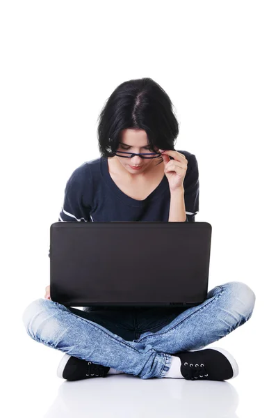 Jovem atraente sentada na frente de um laptop . — Fotografia de Stock