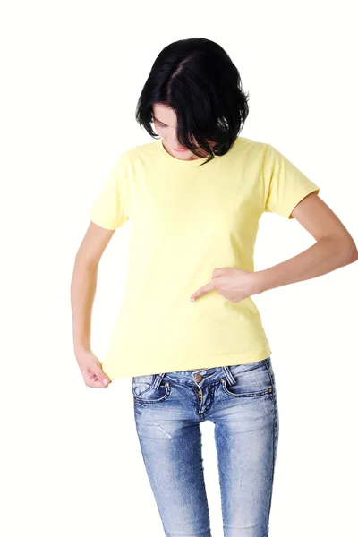 Attraktive junge Frau zeigt auf ihr T-Shirt. — Stockfoto