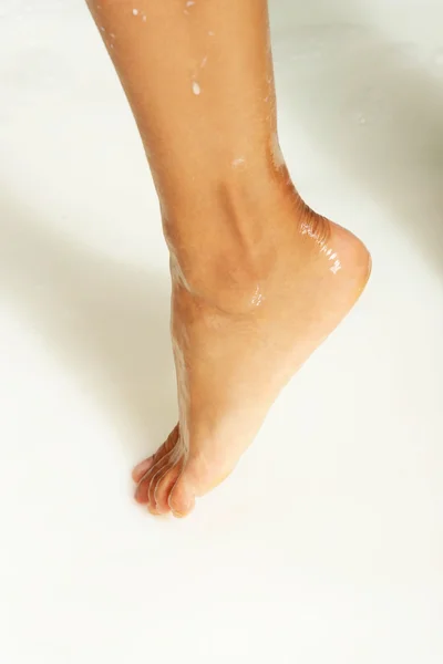 Vrouwelijke natte voet in een bad van melk. — Stockfoto