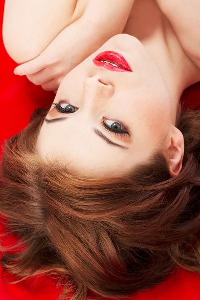 Attractive young naked woman lying on a red background. — Stock Photo, Image