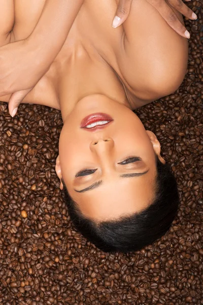 Attractive woman lying upside down on coffee seeds. — Stock Photo, Image