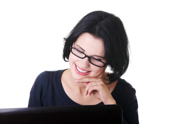 Jovem atraente sentada na frente de um laptop . — Fotografia de Stock