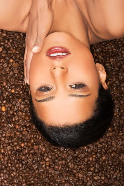 Mulher atraente deitado de cabeça para baixo em sementes de café . — Fotografia de Stock