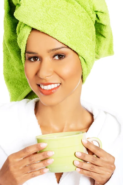 Attractive woman wrapped in towel with turban on head, holding a — Stock Photo, Image