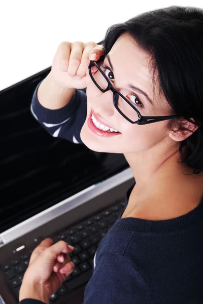 Jovem atraente sentada na frente de um laptop . — Fotografia de Stock