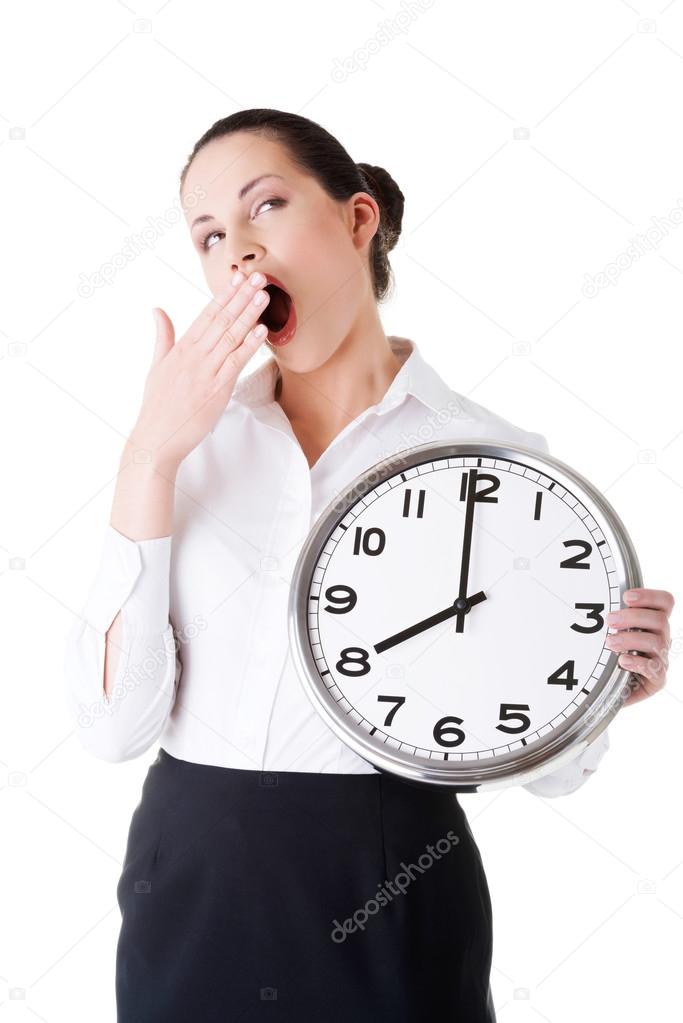 Business woman holding a clock and yeaning.