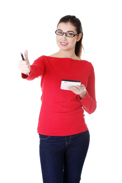 Attractive young woman skowing OK, standing with pen and paper. — Stock Photo, Image