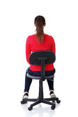 Happy casual woman sitting on a chair. Back view.