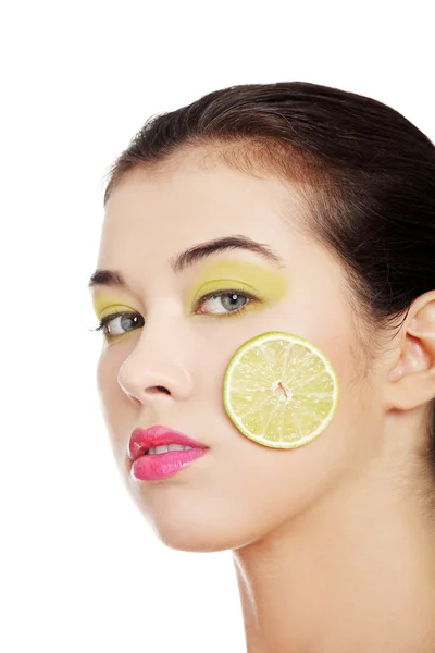 Beautiful woman's face with lime on cheek. — Stock Photo, Image