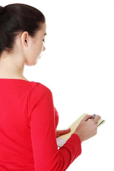 Feliz mujer casual escribiendo en un pedazo de papel. Vista trasera . — Foto de Stock