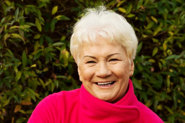 Portret van een vrolijke oude dame op groene achtergrond. — Stockfoto