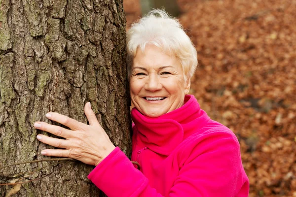 Портрет старушки, стоящей рядом с деревом . — стоковое фото
